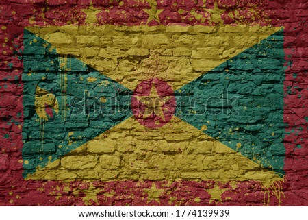 colorful painted big national flag of grenada on a massive old brick wall