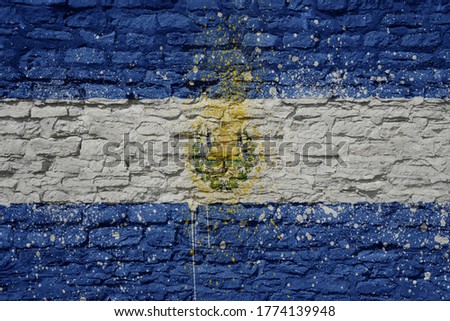 colorful painted big national flag of el salvador on a massive old brick wall