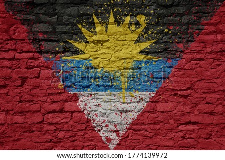 colorful painted big national flag of antigua and barbuda on a massive old brick wall