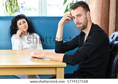 Photo of unhappy loving family conversation of a young man and woman in a room at home sitting at the table