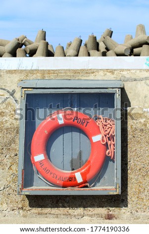 Life ring with inscription Wladyslawowo Port behind a glass. Breakwater in the background. 