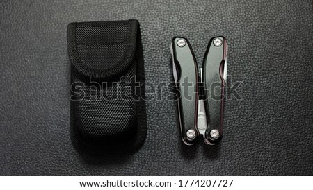 Multitool with a black case on a black leather background Royalty-Free Stock Photo #1774207727
