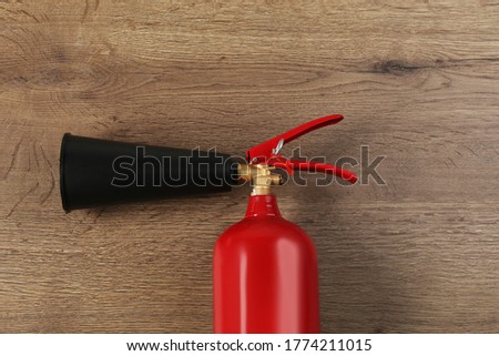 Fire extinguisher on wooden background, top view