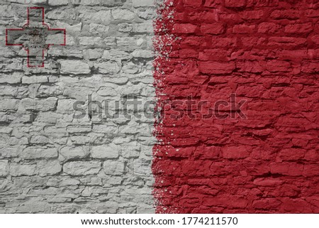 colorful painted big national flag of malta on a massive old brick wall