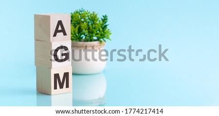 AGM Annual general meeting acronym on wooden cubes on blue backround. Business concept. Royalty-Free Stock Photo #1774217414