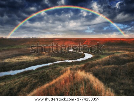 Amazing rainbow over the small rural river. autumn morning

