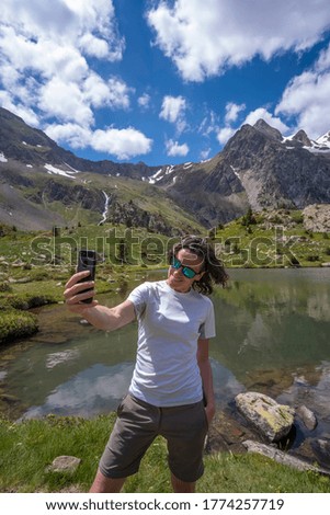 woman taking a selfie with a smartphone on a glacial lake vertical