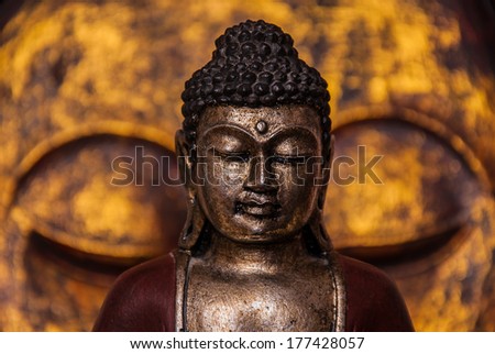 The symbol of the richness, of the founder of Buddhism, Buddha miniature statue sculpture with golden painted wood carved Buddha face on the background, vivid colors Royalty-Free Stock Photo #177428057