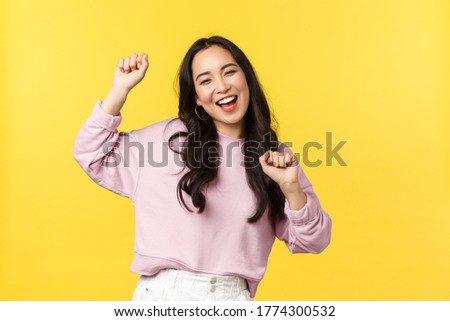 People emotions, lifestyle leisure and beauty concept. Upbeat happy and cheerful asian girl dancing and having fun, partying, moving rhythm music and smiling over yellow background Royalty-Free Stock Photo #1774300532