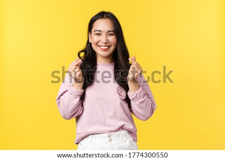People emotions, lifestyle and fashion concept. Kawaii asian girl with beautiful smile showing korean hearts gesture sending positive and joyful vibes, standing yellow advertisement background Royalty-Free Stock Photo #1774300550
