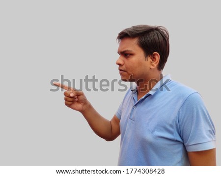 Side view of Man pointing finger curiously left side on isolated grey background
