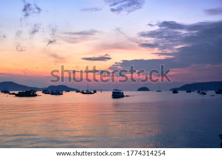 Sea boats on the colorful sea at sunrise. Purple-pink sky with clouds. Phuket. Thailand