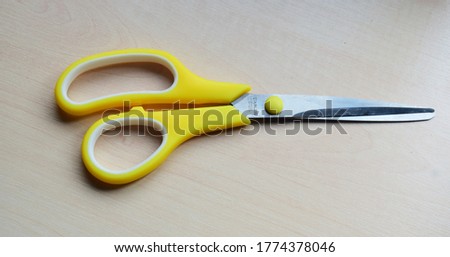 Yellow scissors on wooden table. 