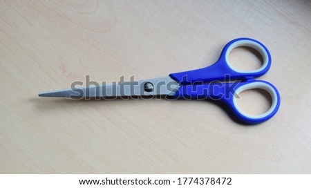 Blue scissors on wooden table. close up scissors.