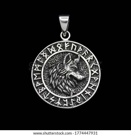 
Futhark. Runes in random order, do not form text. Silver jewelry. Pendant on the neck. Amulet. Occult symbolism. The head of a wolf in a runic circle. 
Paganism of the Vikings. Symbol of courage.