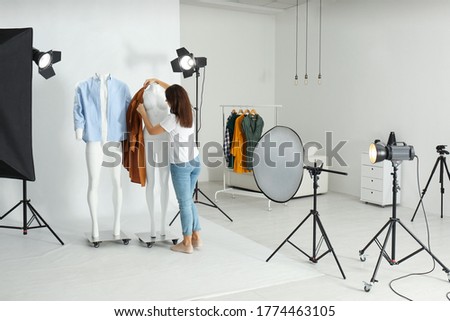 Woman putting clothes on ghost mannequins in professional photo studio