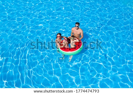 Happy family with inflatable ring in swimming pool. Summer vacation