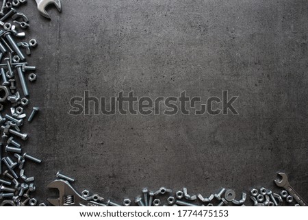 Industrial frame or border made of old nuts and bolts. Grey textured concrete background with copy space. Handyman tools close up picture. Home renovation concept. 

