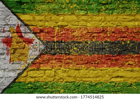 colorful painted big national flag of zimbabwe on a massive old brick wall