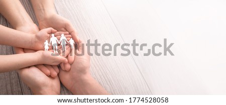 Hands with cut out paper silhouette on table. Family care concept.