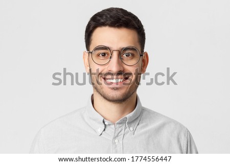 Close-up portrait of young smiling handsome man, feeling confident as professional, isolated on gray background