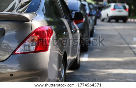 Closeup of rear, back side of brown car with  other cars parking in parking area beside the street in bright sunny day.