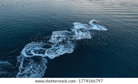 Aerial drone photo of stunt man performing extreme stunts with jet ski water craft over the ocean at dusk