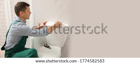 Professional plumber repairing toilet bowl in bathroom, space for text. Banner design