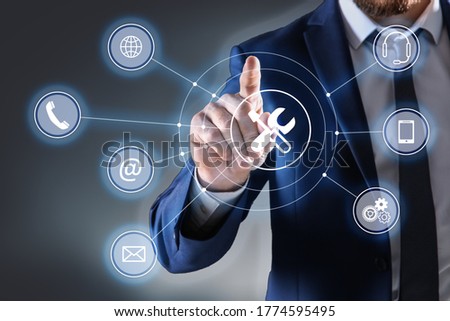 Businessman touching icon on virtual screen against dark background, closeup. Technical support