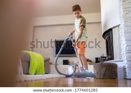 Boy vacuuming floor at home
 Royalty-Free Stock Photo #1774601285