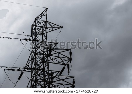 Electricity pylon and high voltage power lines on the road with cloud and overcast sky