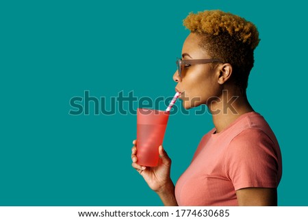 Profile portrait of a cool young  woman in pink holding a drinking cup and paper straw Royalty-Free Stock Photo #1774630685