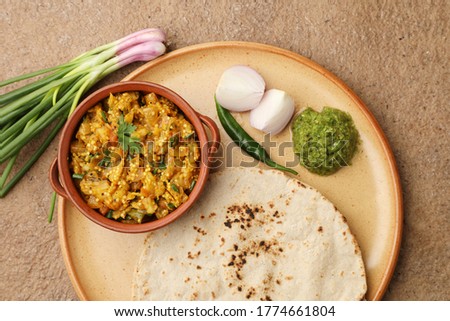 roasted egg plant and bhakri or Indian flat bread served with green chilli chutney traditionally called as Theccha in Marathi and spring onion beside the plate. A  Maharashtrian food Royalty-Free Stock Photo #1774661804