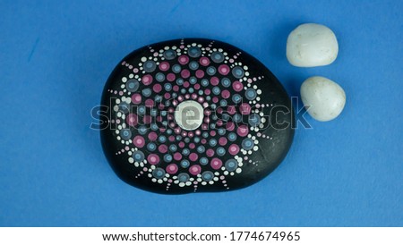 top view of Traditional tribal painting on stone with colourful textured paper background 