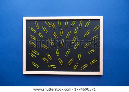 School black board with colored paper clips on the blue background. Back to school concept. Flatlay.