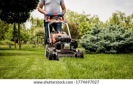 Gardener mowing the lawn. Landscape design. Green grass background Royalty-Free Stock Photo #1774697027