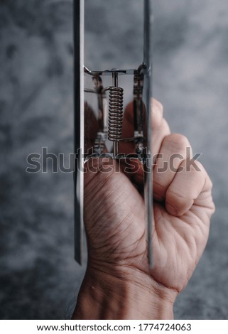 Hand holding metal clip against gray background