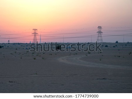 Deserted road with high voltage power lines on background during sunset
