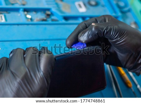 man with black rubber glove repairing mobile phone