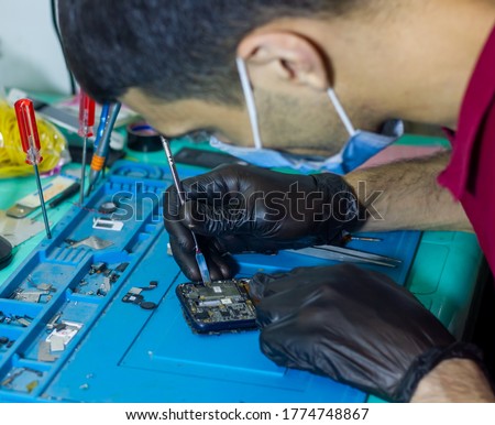 man with black rubber glove repairing mobile phone