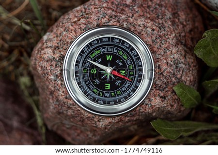 Magnetic compass with a black dial on a stone top view. The concept of travel, finding a path, achievement, hiking, vacation. Copy space