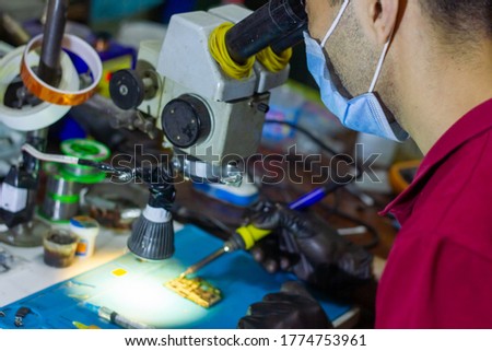 service worker repairing mobile phone with microscope