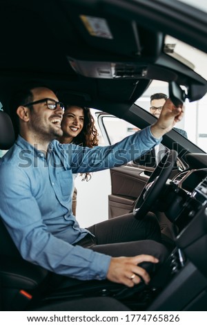 Middle age couple choosing and buying car at car showroom. Car salesman helps them to make right decision. Royalty-Free Stock Photo #1774765826