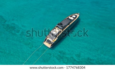 Aerial drone top view photo of black yacht - boat with wooden deck anchored in tropical exotic paradise with turquoise open sea