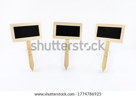 Three empty wooden signs with a black center on a stick stuck in a glass vial, isolated on a white background.