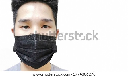 Asian male, gray shirt wearing black mask on isolated background left side of picture 
