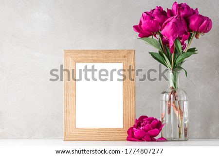 red peony flowers bouquet with blank photo frame on white background. mock up. still life. wedding or holiday concept. festive background