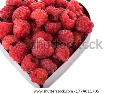 Ripe raspberries in shape of heart isolated on white background. Copy space. Border style. Close up.