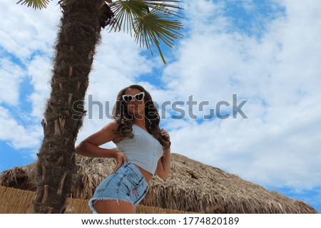 Amazing girl with a perfect figure in sunglasses near a palm tree