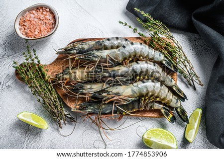 Black raw tiger prawns, shrimps on a cutting board. Gray background. Top view Royalty-Free Stock Photo #1774853906